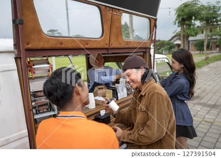 Chinese muslim female in a hijab waiter serving food to Indonesian southeast asian customers. A small business on a truck 127391504