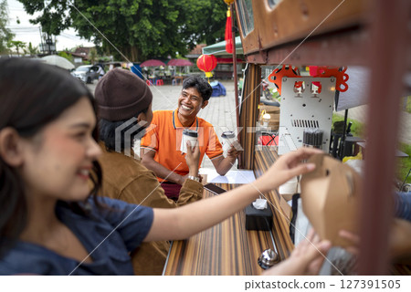 Female waiter serving food to an Indonesian southeast asian customers. A small business on a truck Female waiter serving food to an Indonesian southeast asian customers. A small business on a truck 127391505