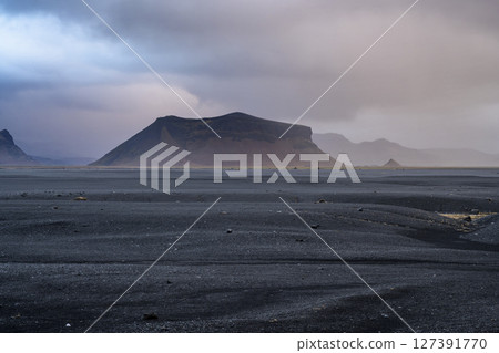 Panoramic view of black sand beach and mountain range landscapes with dramatic sky on Solheimasandur, Iceland. Nature, travel, winter background, or wallpaper 127391770