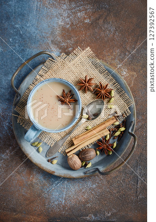 Indian masala chai tea. Spiced tea with milk on dark rusty background. Indian masala chai tea. Spiced tea with milk on dark rusty background. 127392567