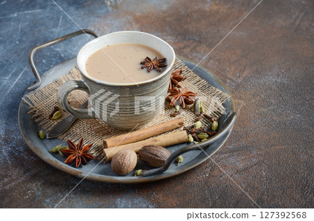 Indian masala chai tea. Spiced tea with milk on dark rusty background. Indian masala chai tea. Spiced tea with milk on dark rusty background. 127392568