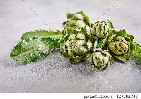 Fresh organic artichokes on a gray concrete background. Fresh organic artichokes on a gray concrete background. 127392748