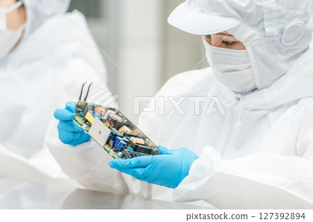 Female handling precision equipment in a clean room Female handling precision equipment in a clean room 127392894