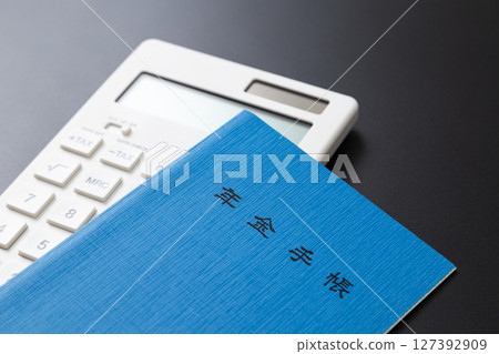 黑色背景中的計算器和退休金書 黑色背景中的計算器和退休金書 127392909