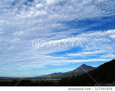 White disk-shaped scale clouds spread across the sky above Mount Bandai, creating an impressive and beautiful sight against the blue autumn sky. 127392958
