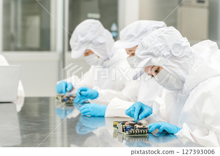 穿著防塵服的男女工人在無塵室操作精密設備 穿著防塵服的男女工人在無塵室操作精密設備 127393006