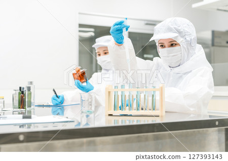 Staff wearing clean suits developing drugs at a pharmaceutical factory or pharmaceutical company 127393143