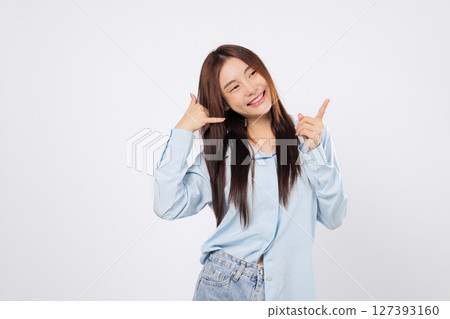 Gesture of call me made by woman using hand and fingers, second woman winks while pretending to talk on a telephone and pointing finger, isolated white background. Gesture of call me made by woman using hand and fingers, second woman winks while pretending to talk on a telephone and pointing finger, isolated white background. 127393160