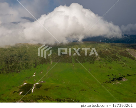 Big white clouds over a green mountain valley Big white clouds over a green mountain valley 127393261