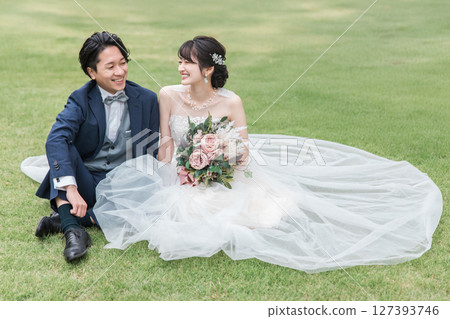 身著婚紗的新娘和新郎坐在禮堂花園的草坪上（婚紗照） 127393746
