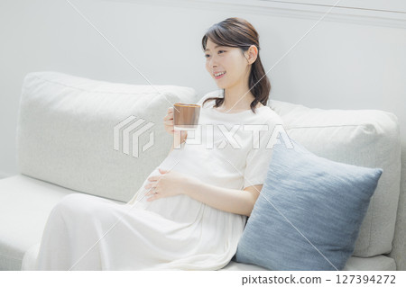 Pregnant woman drinking beverage in room 127394272
