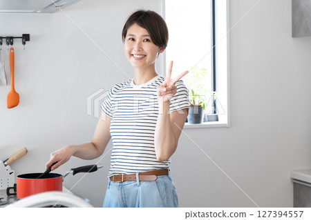 微笑的女人在廚房做飯時做出和平手勢 127394557