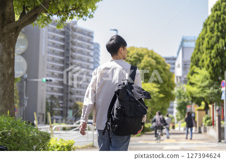 一名 40 多歲的男子背著背包走在街上，背影 127394624