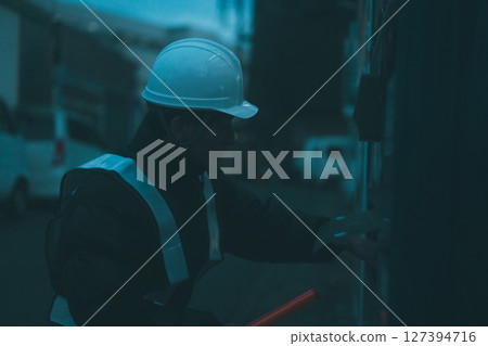 A security guard on a break putting his hand into the dispenser of a vending machine 127394716