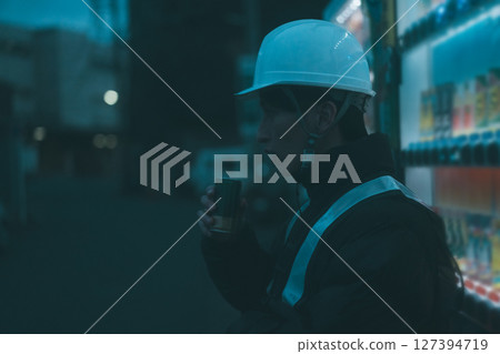 A security guard on a break drinking a can of coffee 127394719