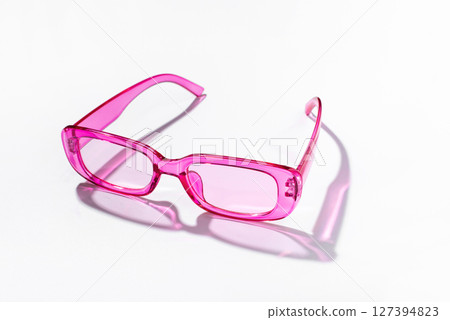 Stylish pink sunglasses with transparent glass on a white background 127394823