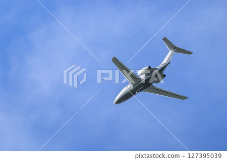 Private jet flying high in the blue sky over Hostivice, Czechia 127395039