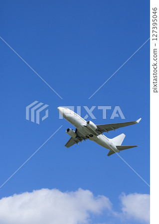 White passenger airplane flying high in blue sky over white clouds White passenger airplane flying high in blue sky over white clouds 127395046