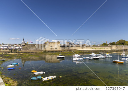 Concarneau Ville Close reflecting in the water with moored boats during a sunny day 127395047