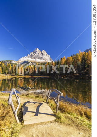 Wooden bridge leading to Lake Antorno with Tre Cime di Lavaredo reflecting in the water during autumn Wooden bridge leading to Lake Antorno with Tre Cime di Lavaredo reflecting in the water during autumn 127395054