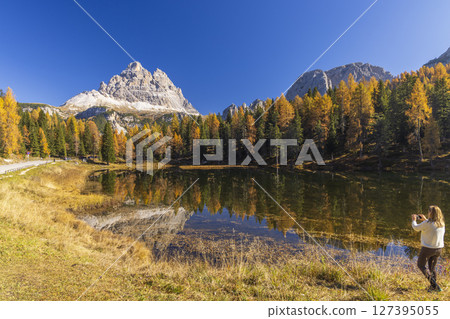 Tre Cime di Lavaredo reflecting on Lake Antorno with colorful larch trees during fall foliage in Dolomites, Italy 127395055