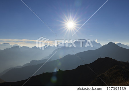 Stunning view of sun shining over mountain peaks range in the Dolomites, Italy Stunning view of sun shining over mountain peaks range in the Dolomites, Italy 127395189