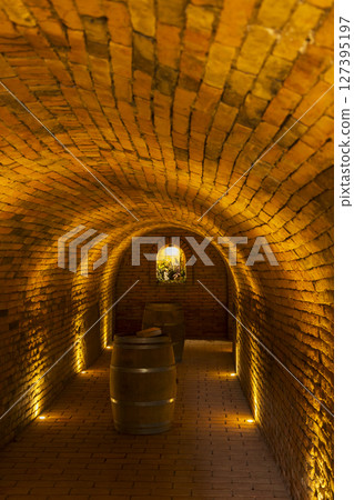 Wine cellar with wooden barrels illuminating warm light creating cozy atmosphere Wine cellar with wooden barrels illuminating warm light creating cozy atmosphere 127395197