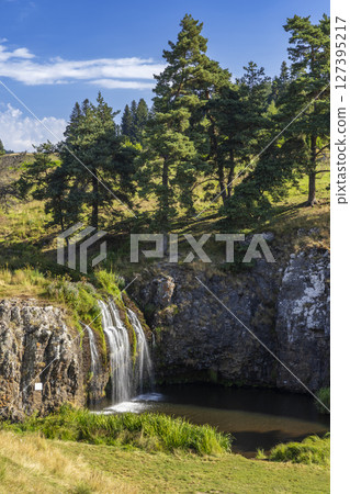 Waterfall cascading down rocky cliffs in Saint Sulpice les Champs, France, creating a picturesque landscape 127395217