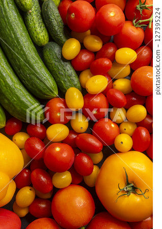 Freshly picked cucumbers, tomatoes and bell peppers creating a colorful composition 127395224