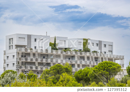 Modern white building rising above green trees in Montpellier, France Modern white building rising above green trees in Montpellier, France 127395312
