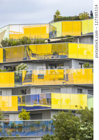 Modern building with yellow and blue glass balconies reflecting the sky in Montpellier, France Modern building with yellow and blue glass balconies reflecting the sky in Montpellier, France 127395314