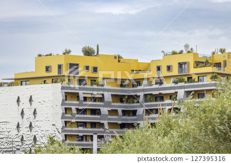Modern building with yellow facade and rooftop vegetation in Montpellier, France Modern building with yellow facade and rooftop vegetation in Montpellier, France 127395316