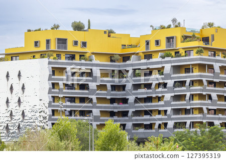 Modern building with yellow facade and balconies featuring plants in Montpellier, France 127395319