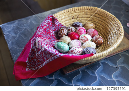 Colorful easter eggs resting in wicker basket with red bandana in Kourim, Czechia 127395391