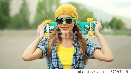 Stylish young woman with skateboard smiles, happy modern teenage girl posing outdoors 127395449