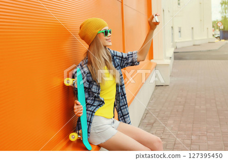 Happy stylish young woman taking selfie with phone, cheerful cool girl smiles using smartphone 127395450