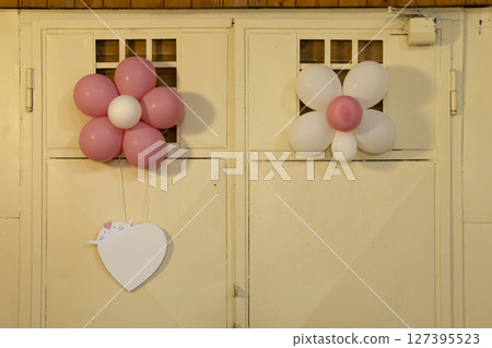 Pink and white flower shaped balloons hanging on a wall with heart shaped label Pink and white flower shaped balloons hanging on a wall with heart shaped label 127395523