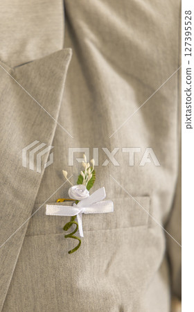 Groom wearing light gray suit with white boutonniere and ribbon on lapel Groom wearing light gray suit with white boutonniere and ribbon on lapel 127395528