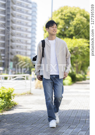 A man in his early 40s walking down the street 127395589