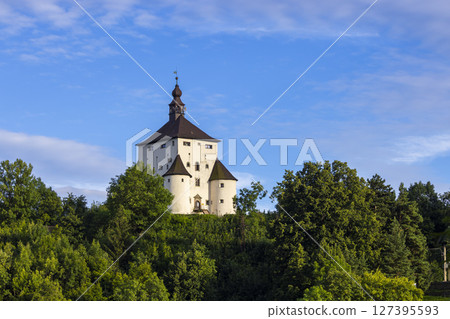 New Castle in Banska Stiavnica rising above green trees under blue sky in Slovakia 127395593