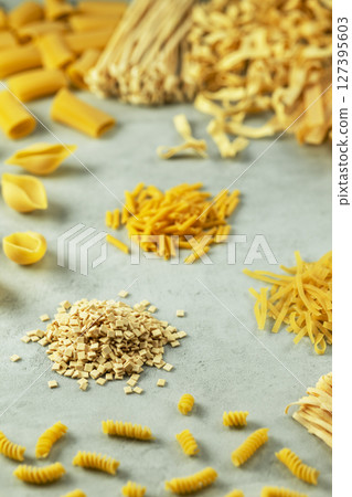 Various types of italian pasta forming a colorful composition on a light blue background Various types of italian pasta forming a colorful composition on a light blue background 127395603