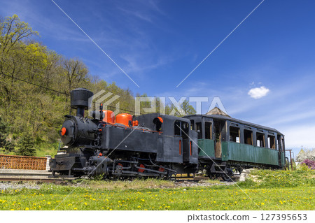 Old steam locomotive with passenger car standing on narrow gauge railway in Slovakia Old steam locomotive with passenger car standing on narrow gauge railway in Slovakia 127395653