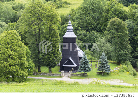 Wooden church of Saint Michael Archangel rising above the trees in Dukla, Poland Wooden church of Saint Michael Archangel rising above the trees in Dukla, Poland 127395655