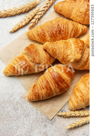 Freshly baked croissants with wheat on baking paper Freshly baked croissants with wheat on baking paper 127395683