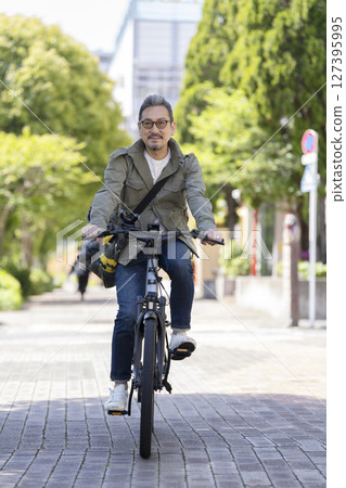 A man in his late 50s riding a bicycle A man in his late 50s riding a bicycle 127395995