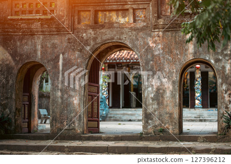 Historic Vietnamese temple entrance with ancient archways and cultural architecture, Traditional spiritual gateway in old Vietnamese temple with weathered stone and sacred atmosphere Historic Vietnamese temple entrance with ancient archways and cultural architecture, Traditional spiritual gateway in old Vietnamese temple with weathered stone and sacred atmosphere 127396212