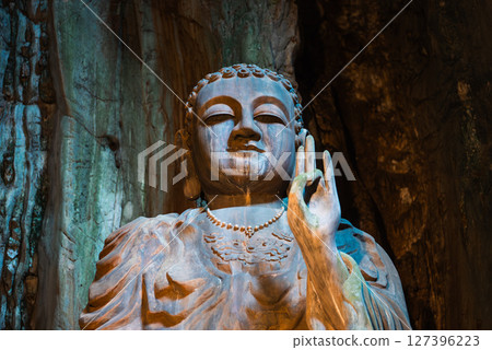 Buddha statue in colorful cave of Marble Mountains with natural light, Sacred sculpture surrounded by vibrant rocks in Marble Mountains cave 127396223
