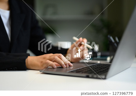 Businessperson working on laptop with digital interface icons, symbolizing data analytics, and global connectivity 127396779