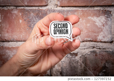 Second Opinion Text in Speech Bubble Held by Hand Against Brick Wall Background 127397232