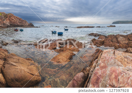Seascape with Vietnamese round basket boats floating in the sea next to rocks 127397928